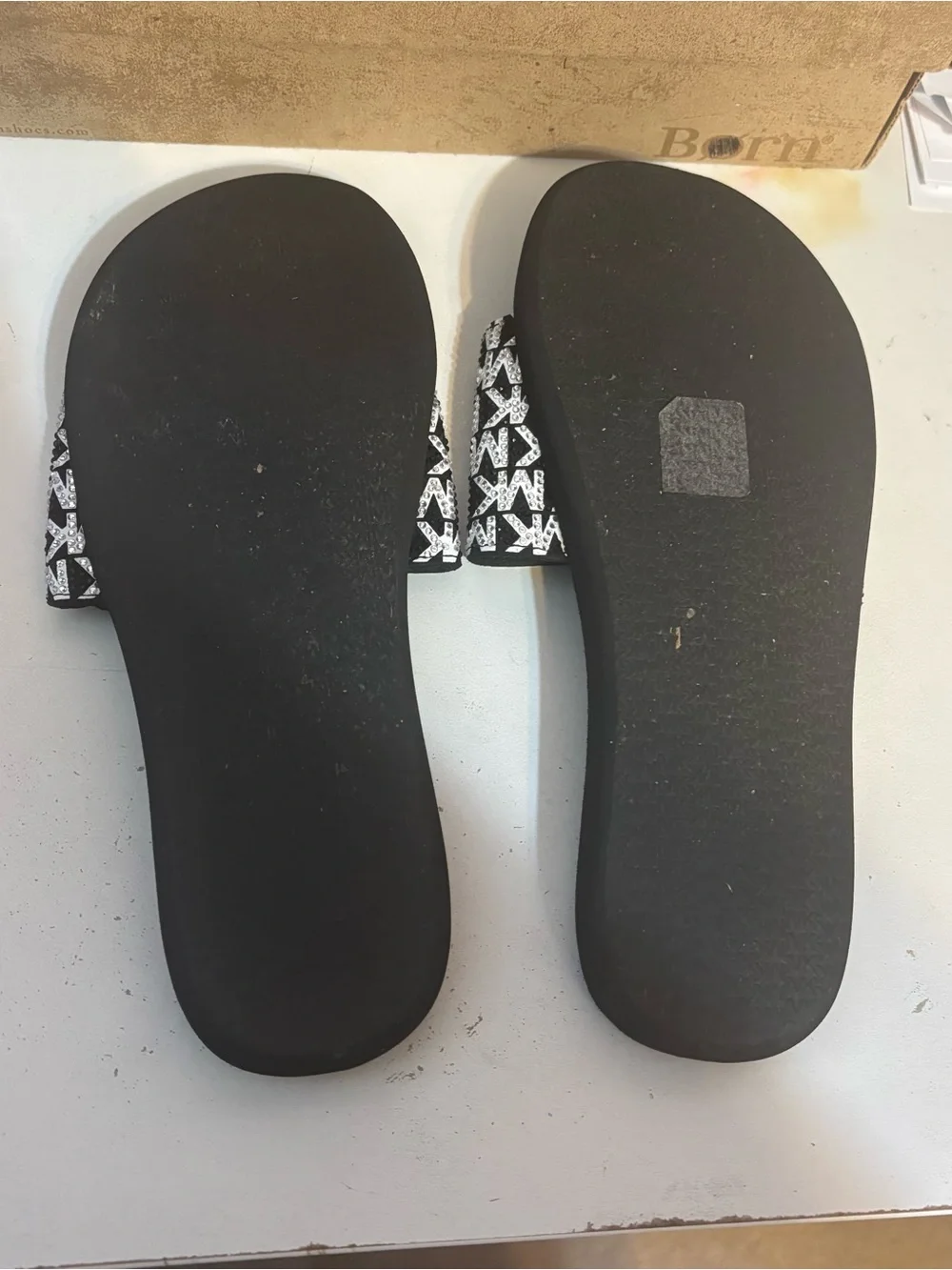 Michael Kors black & white slides featuring a signature logo print on the strap.